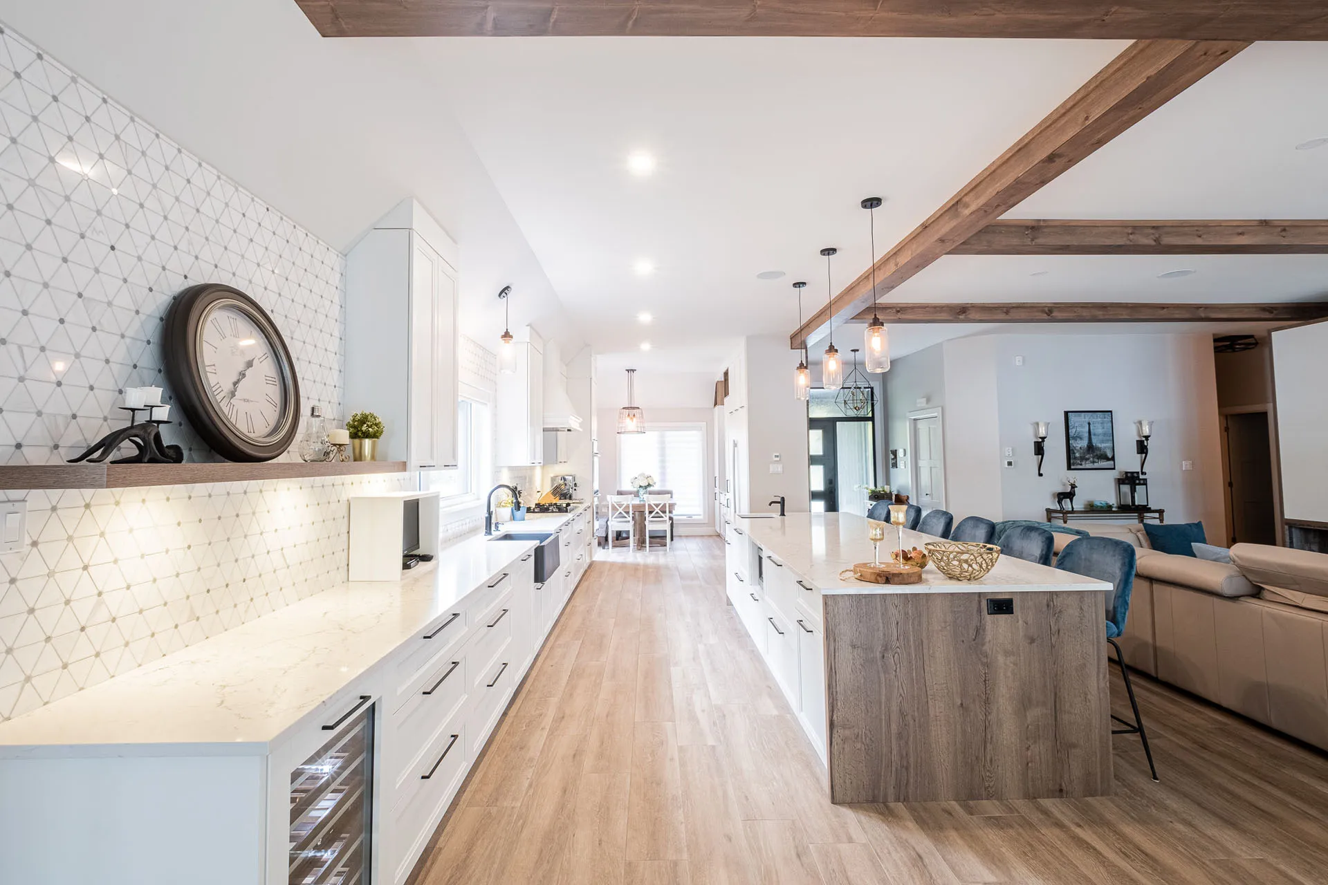 Modern Simard kitchen: white cabinetry, gray wood island, white countertops, geometric backsplash, exposed beams