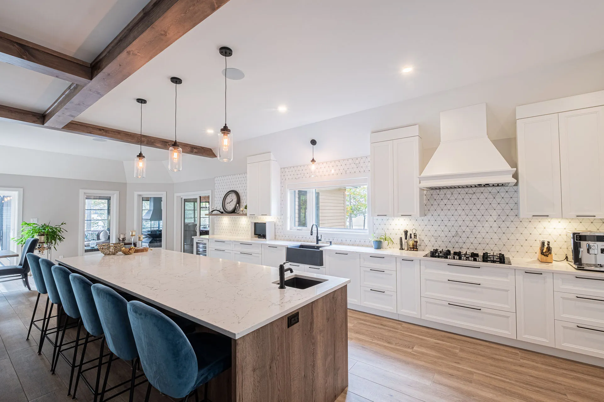 Modern white kitchen with wood island, marble countertop, geometric tile backsplash and pendant lights