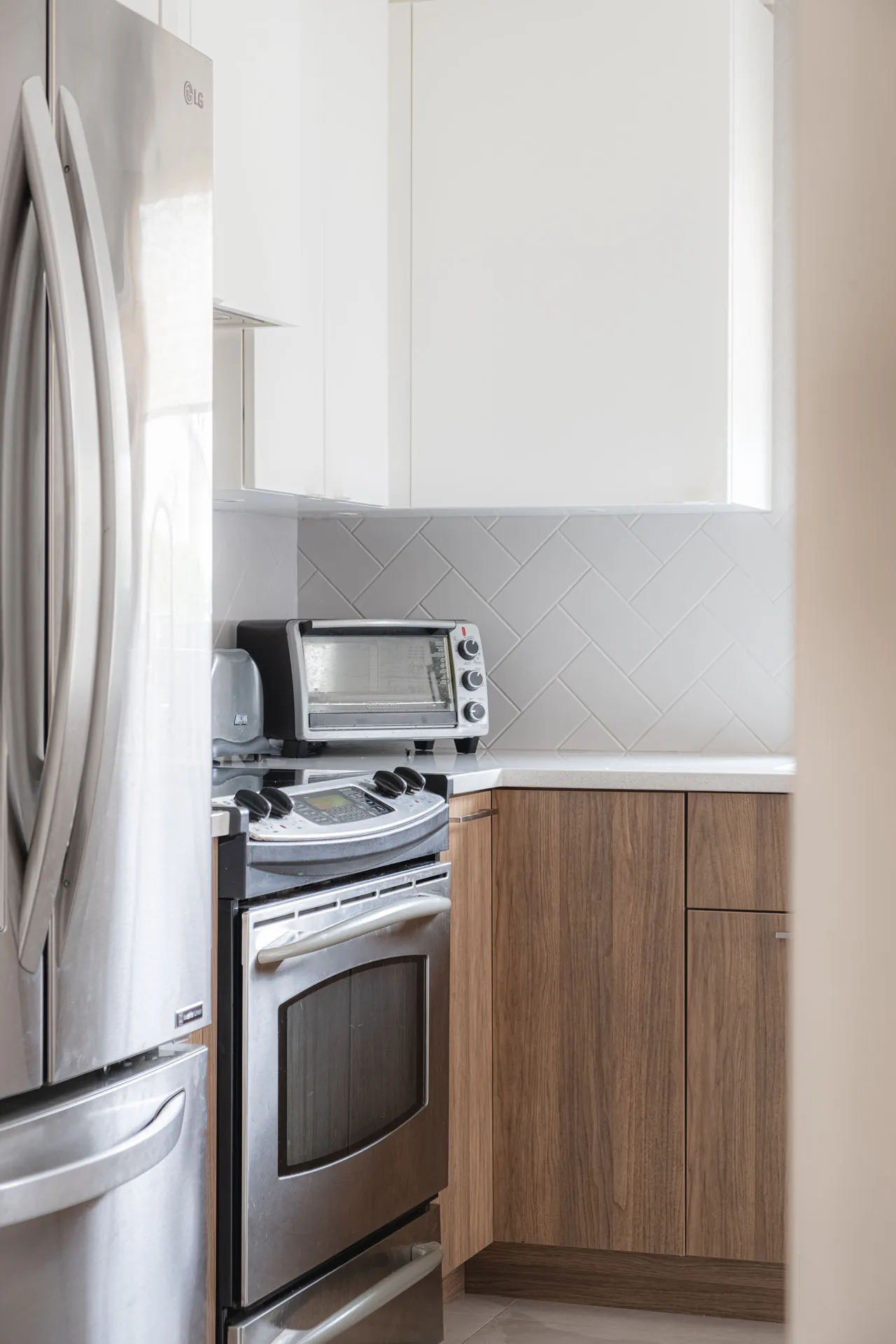 Modern Rosemère kitchen: wood cabinets, white countertop, herringbone tile backsplash, stainless steel appliances