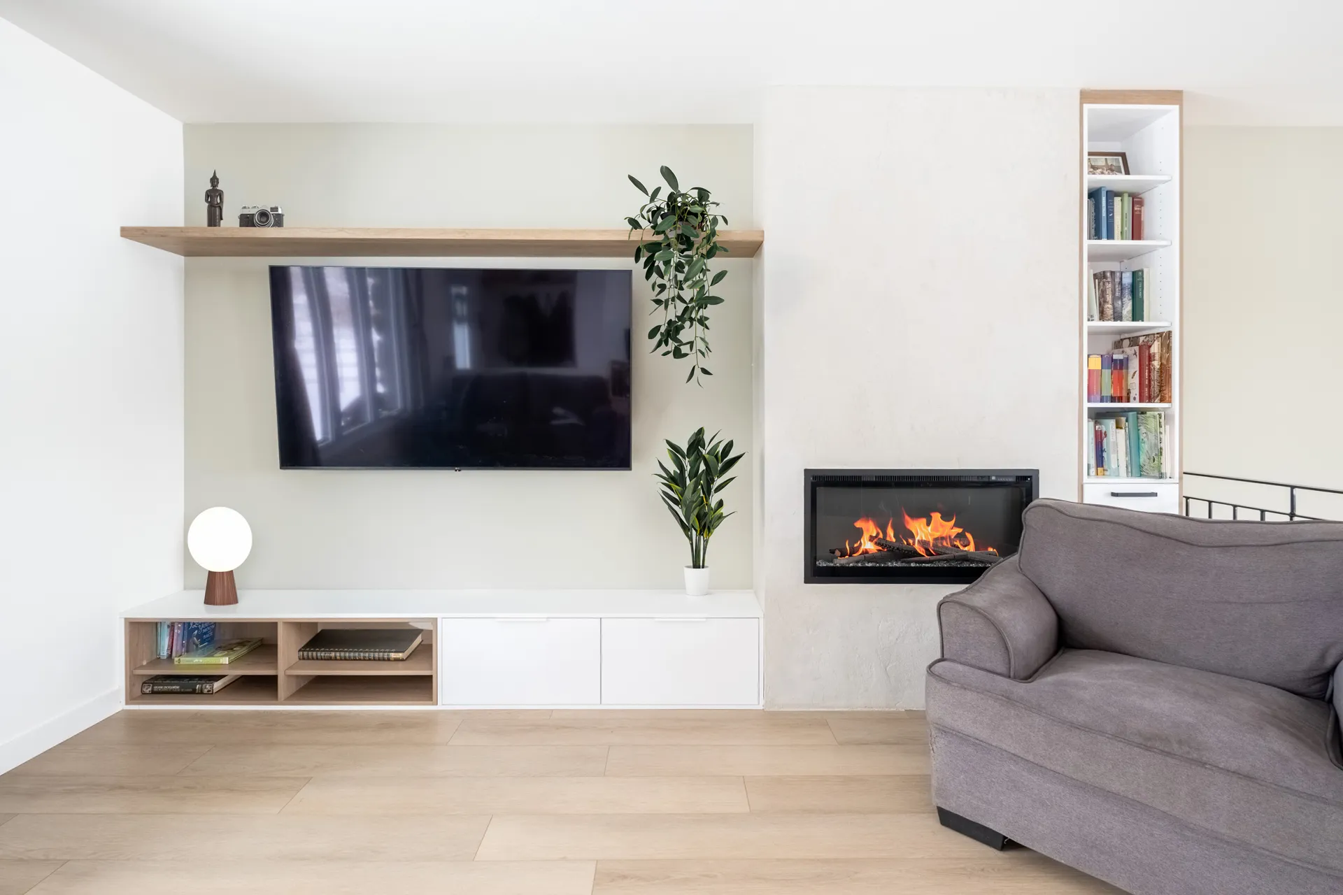 Salon moderne avec meuble TV blanc et bois, foyer électrique, étagères de rangement et bibliothèque intégrée