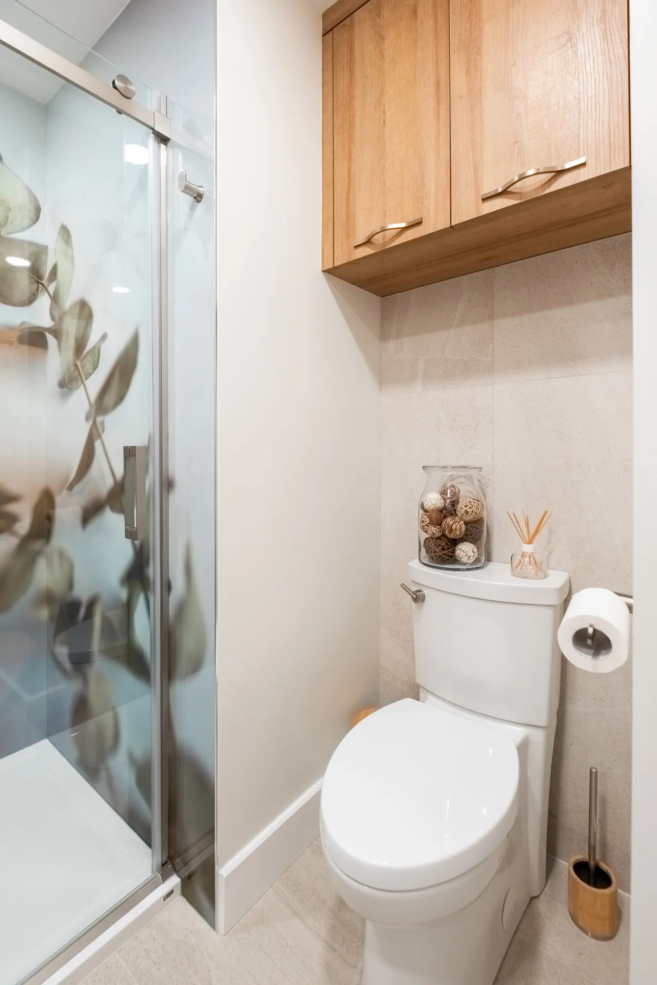 Salle de bain moderne avec armoires en bois naturel, comptoir blanc, dosseret beige et toilette blanche - Projet Forand Laval