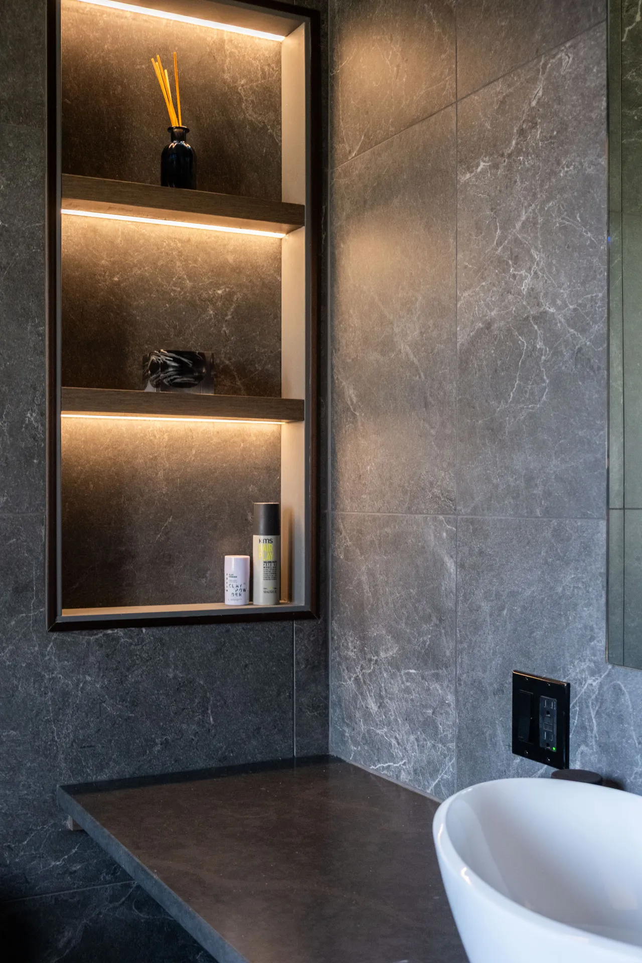 Salle de bain Garraud Rosemère : armoires noires, comptoir gris anthracite, niches éclairées LED, carrelage marbre