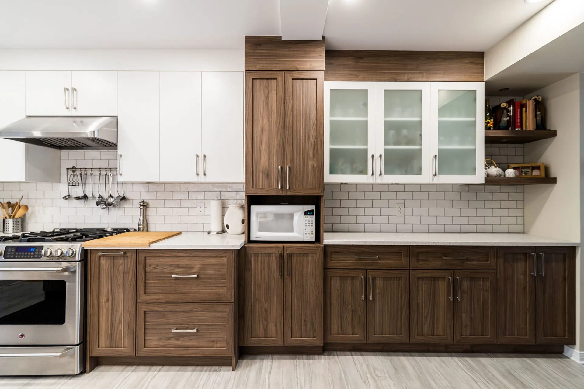 Menuitech renovated kitchen with white and walnut cabinetry, wood countertop, grey subway backsplash, central island.