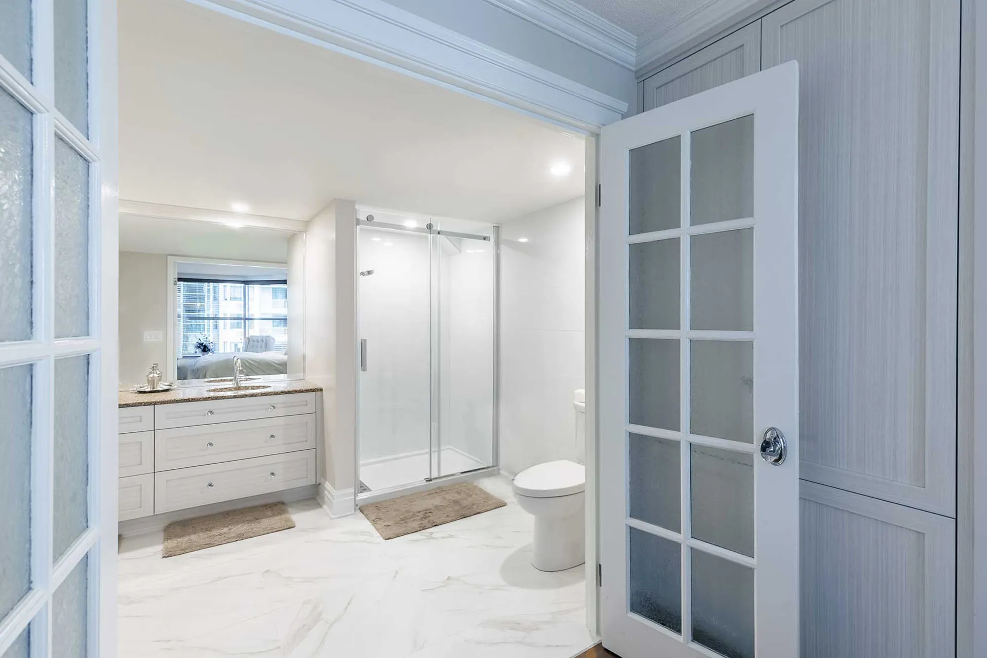 Modern bathroom with white cabinetry, granite countertop, glass shower enclosure and toilet, McDuff project Repentigny