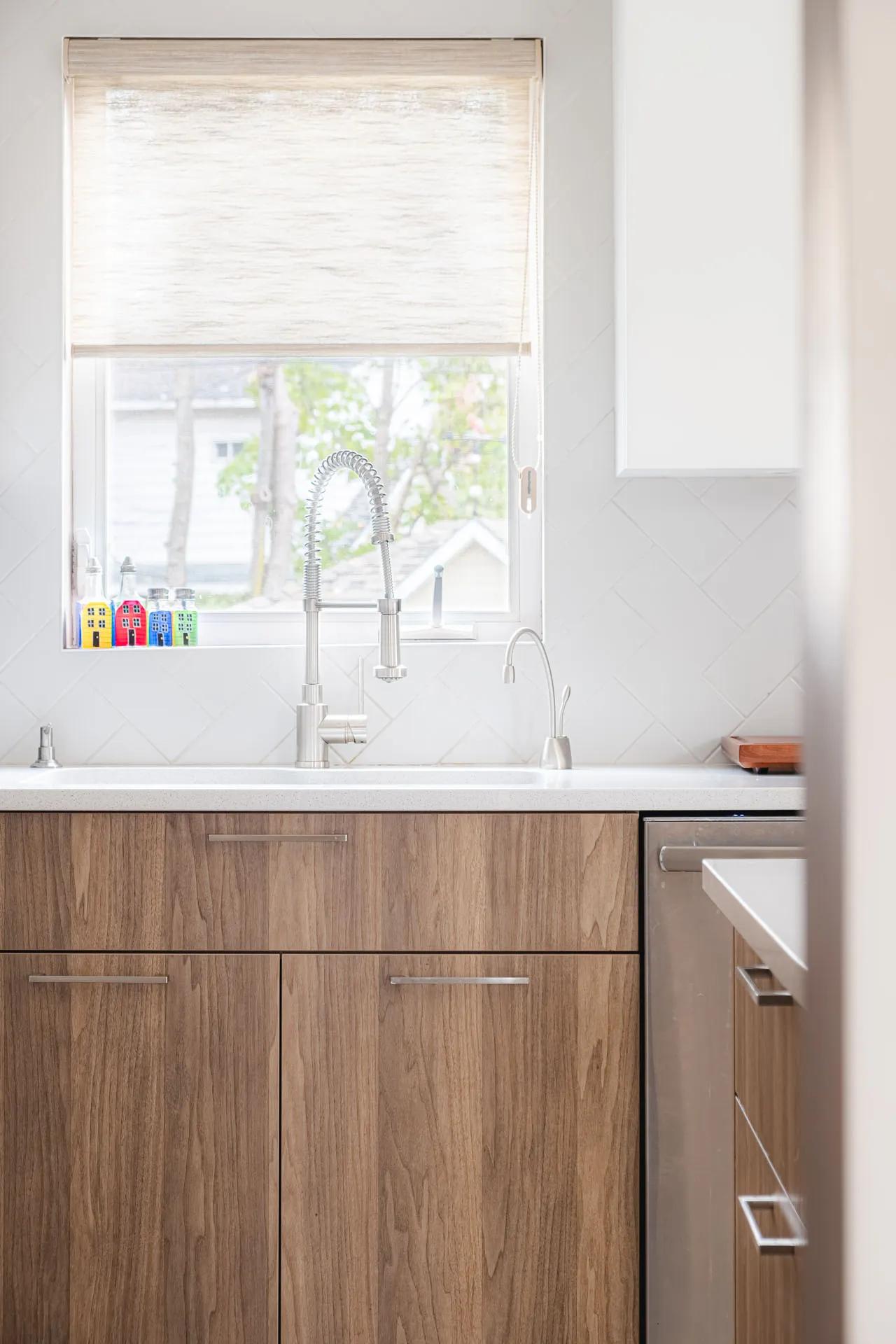 Rosemere kitchen: light wood cabinets, white countertop, herringbone tile backsplash, window with shade