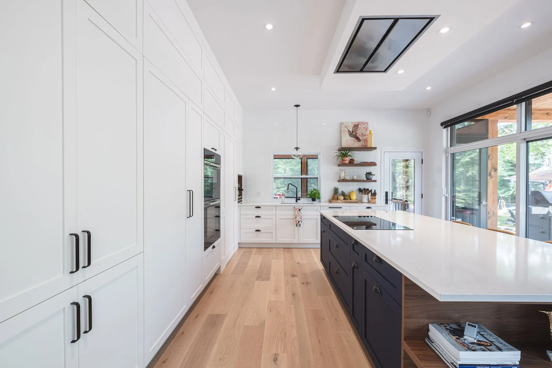 Modern kitchen with white and black cabinetry, white countertops, custom island, white subway tile backsplash by Menuitech