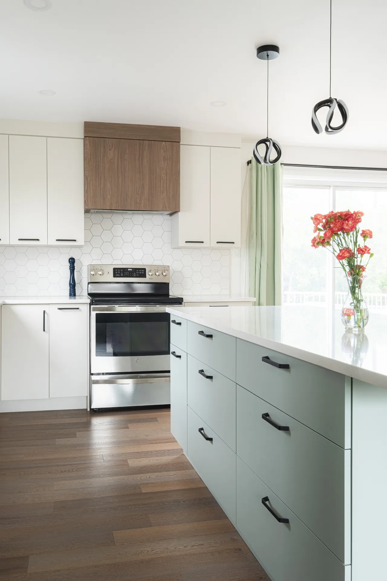 Modern Barrett-Toth kitchen: white and mint cabinetry, hexagonal backsplash, island with white countertop, stainless steel stove, pendant lights