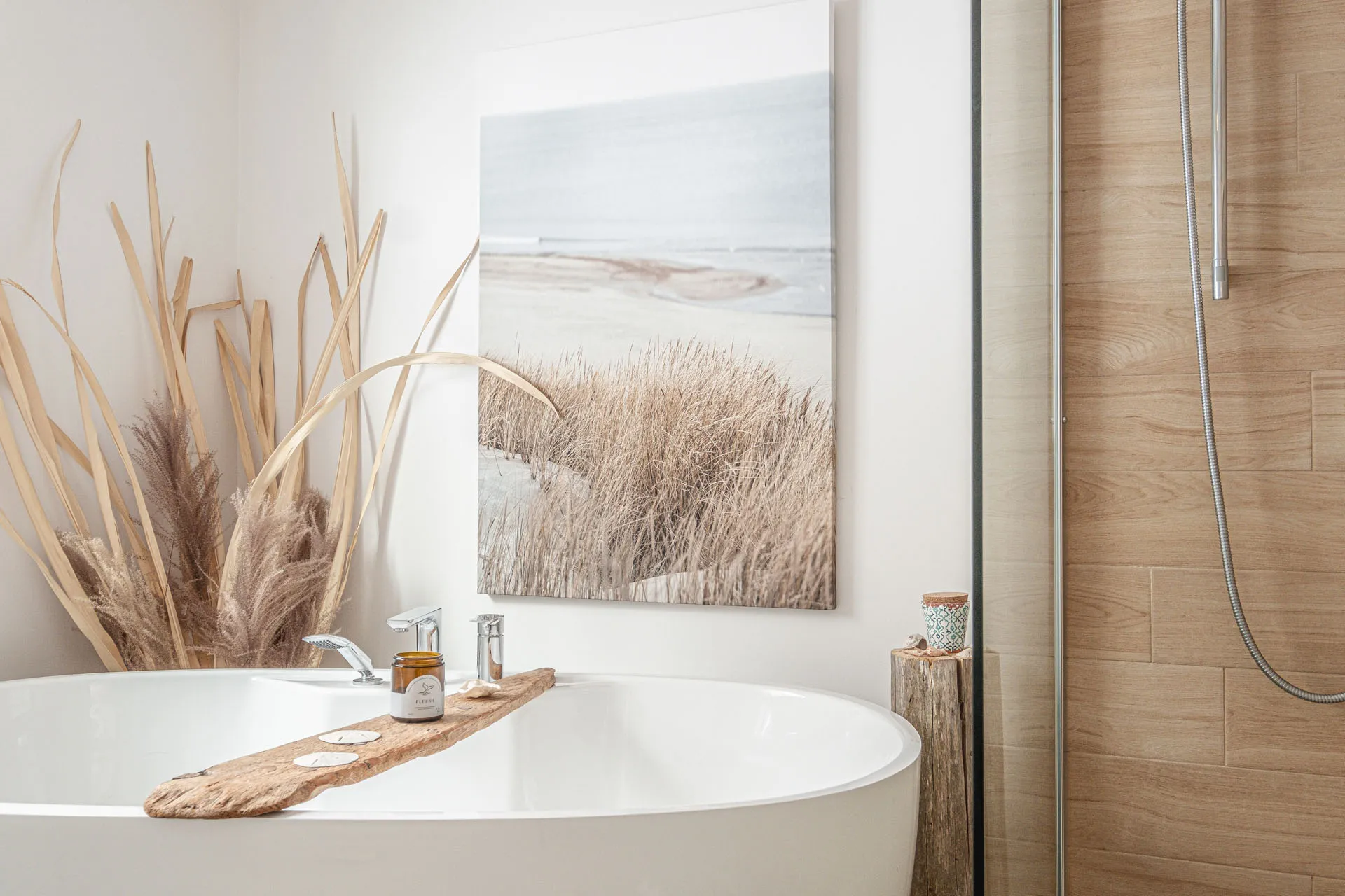 Modern bathroom with white soaking tub, wooden vanity, beige tile, and coastal wall art.