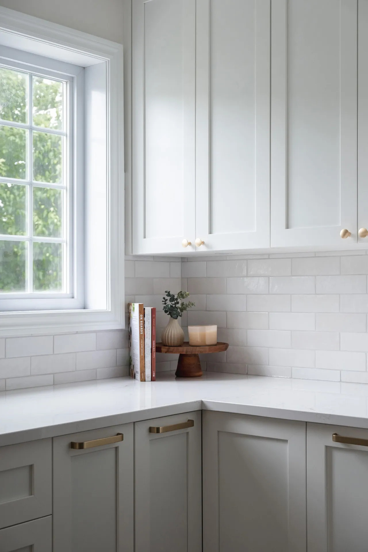 Modern Menuitech kitchen with grey and white cabinets, white countertop, white subway backsplash, window and wooden storage
