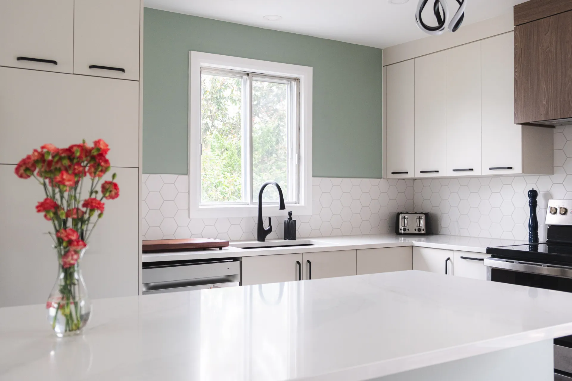 Modern white kitchen with Menuitech cabinets, white countertop, hexagonal backsplash, island, window, black faucet