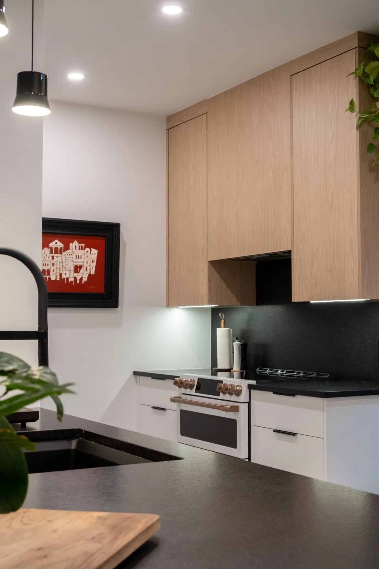 Cuisine Pelletier Montréal : armoires chêne naturel et blanches, comptoir noir, dosseret gris, luminaires suspendus