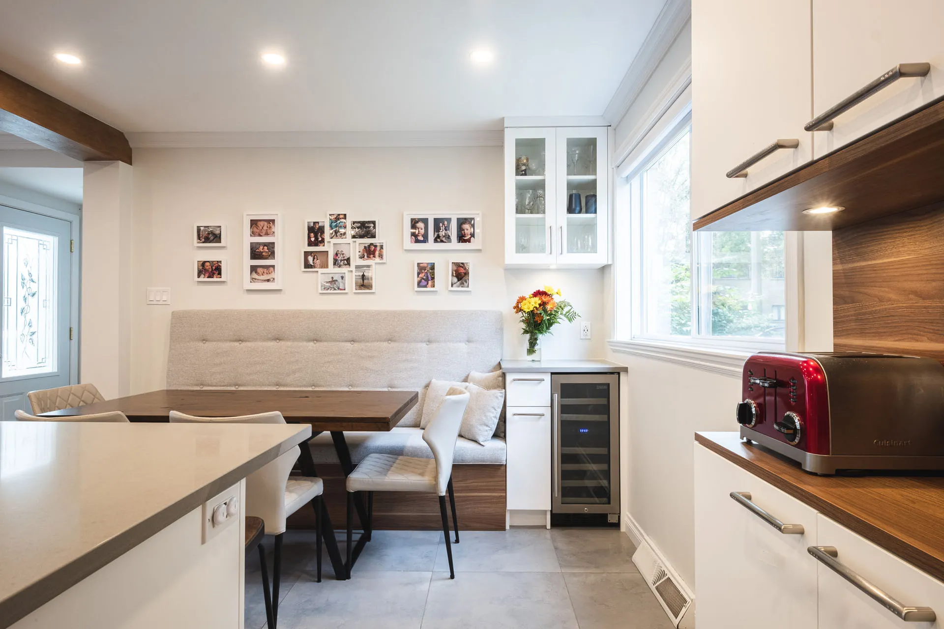 Modern Tardif kitchen with white cabinetry, wood countertops, central island and integrated gray banquette.
