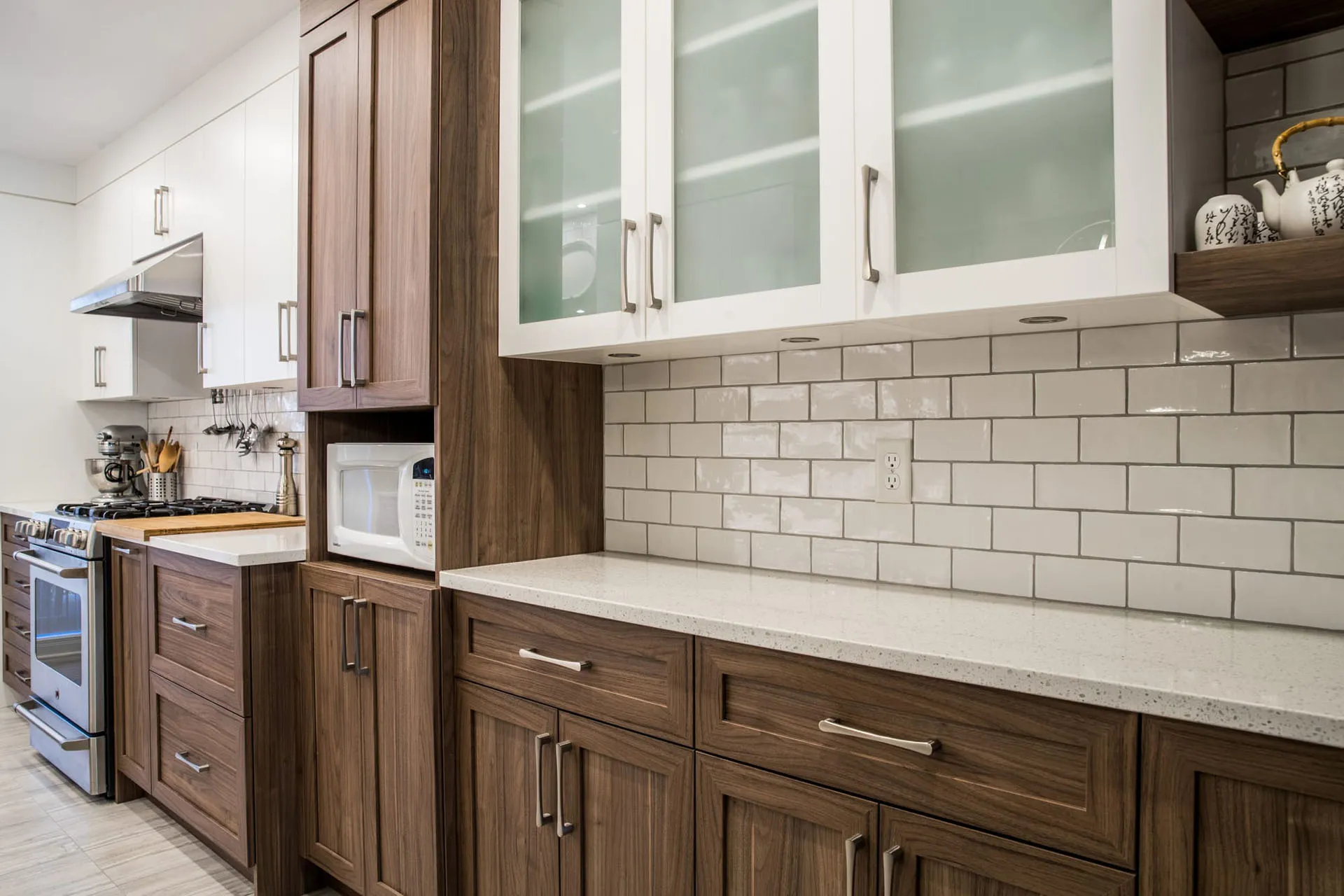Mathieu Kitchen Montreal: dark walnut cabinets, white glass-front doors, grey quartz countertop, subway tile backsplash