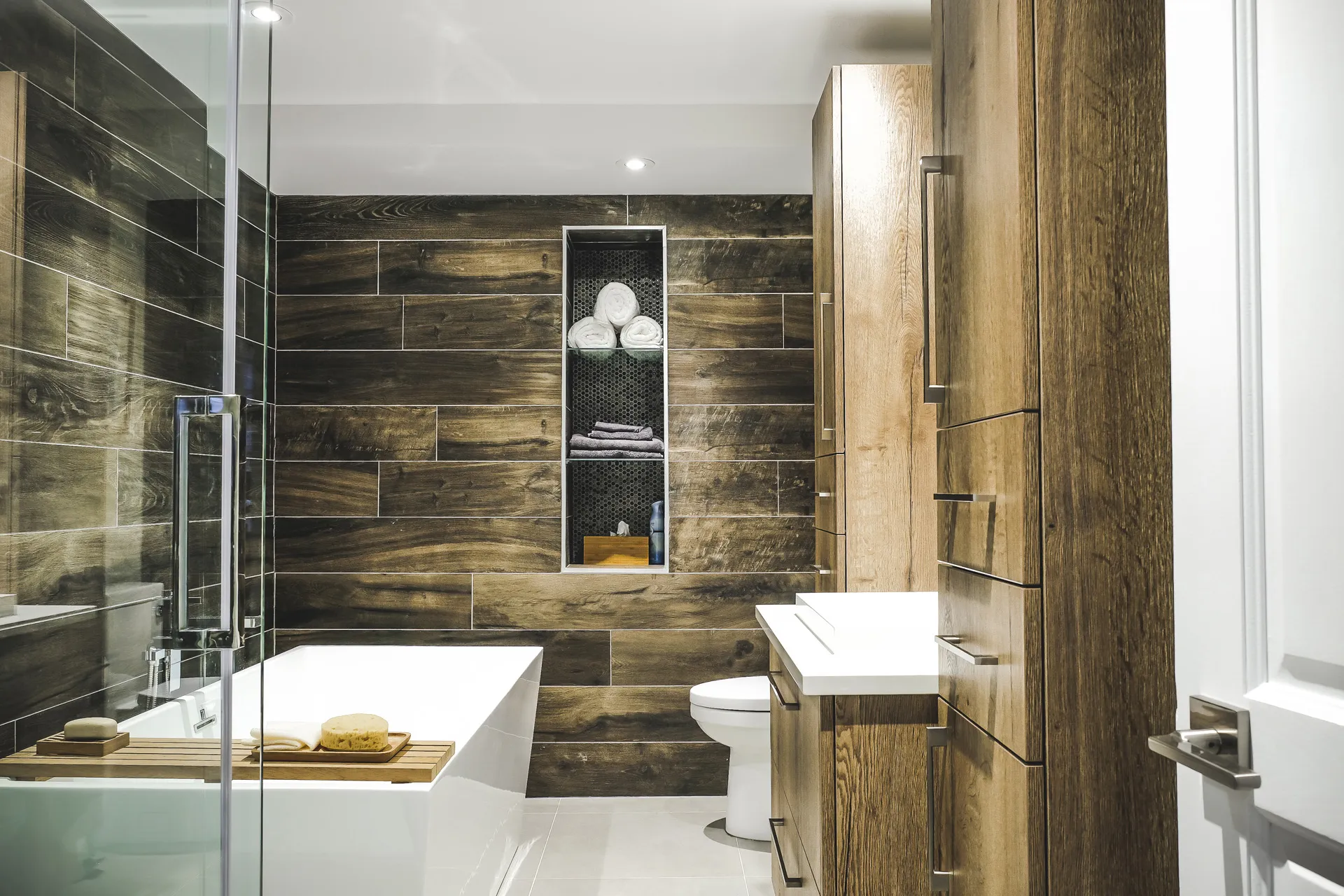 Modern Phaneuf bathroom Laval: dark wood cabinets, white countertop, wood backsplash, built-in bathtub, toilet, glass shower enclosure