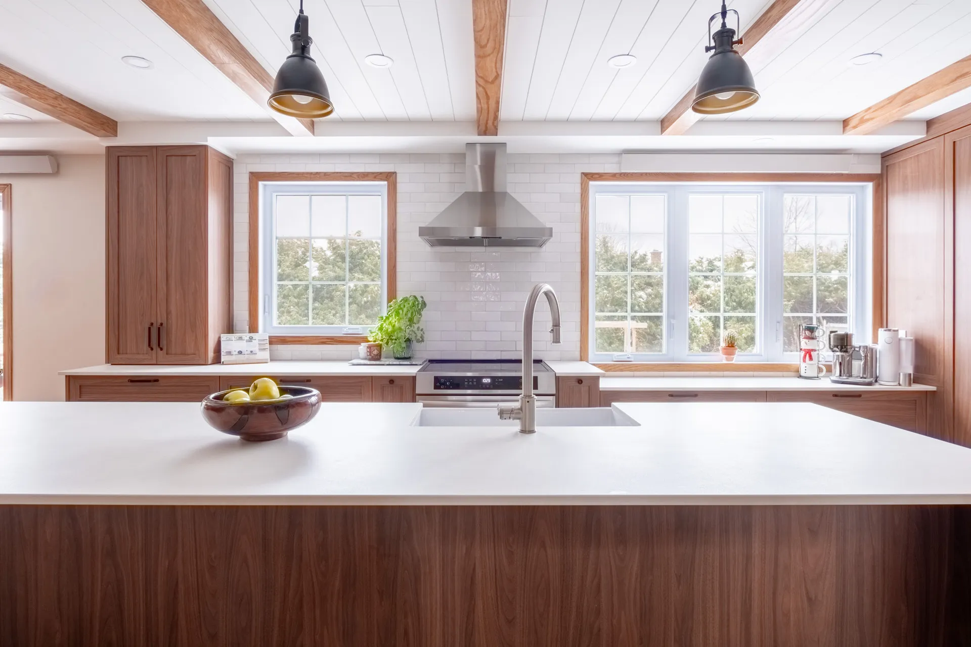 Lemay kitchen Laval: wood cabinets, white countertop, island, subway tile backsplash, black pendant lights, large windows