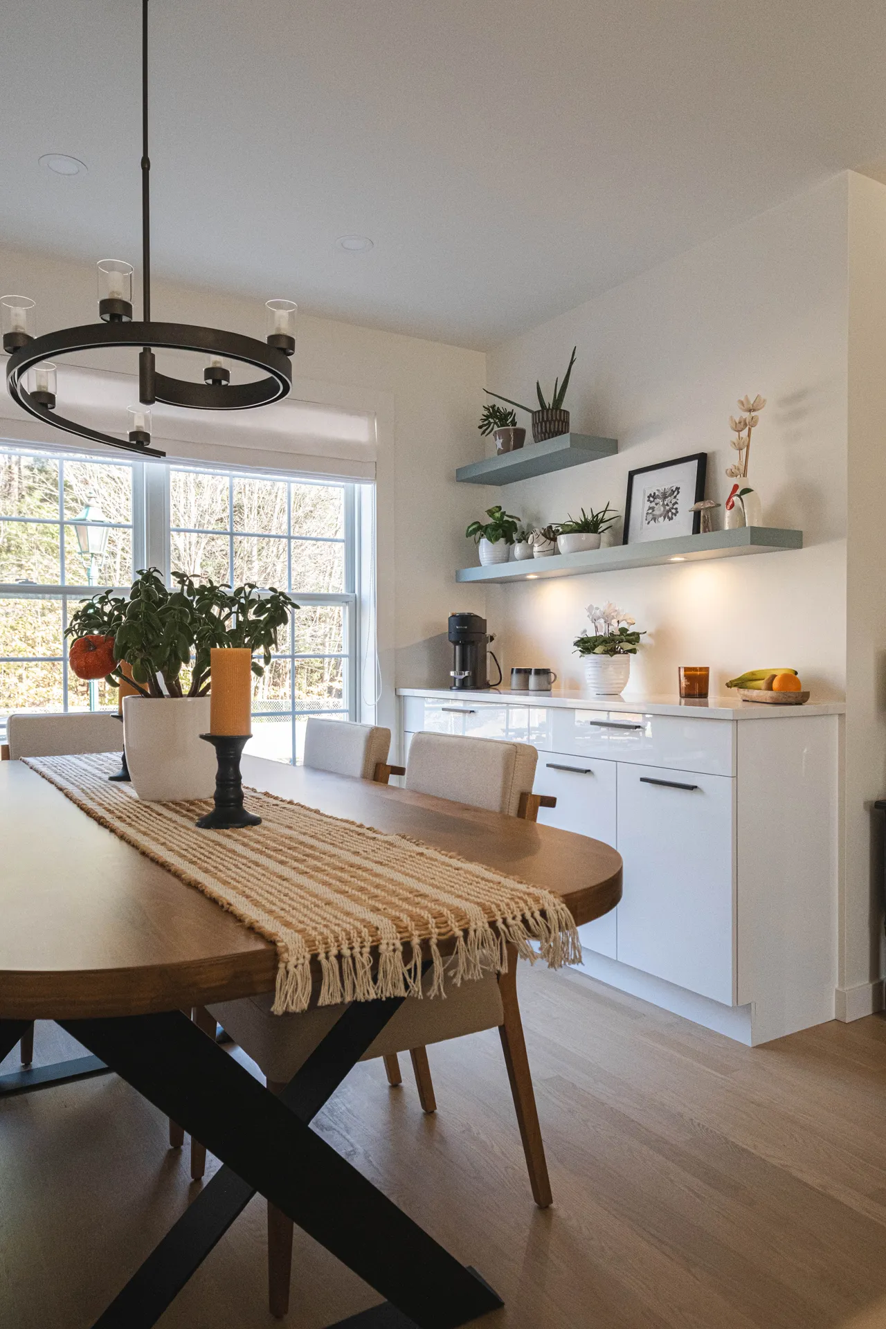 Cuisine moderne Diamant Menuitech : armoires blanches, comptoir bois, table ovale, îlot gris, étagères ouvertes, luminaire suspendu noir.