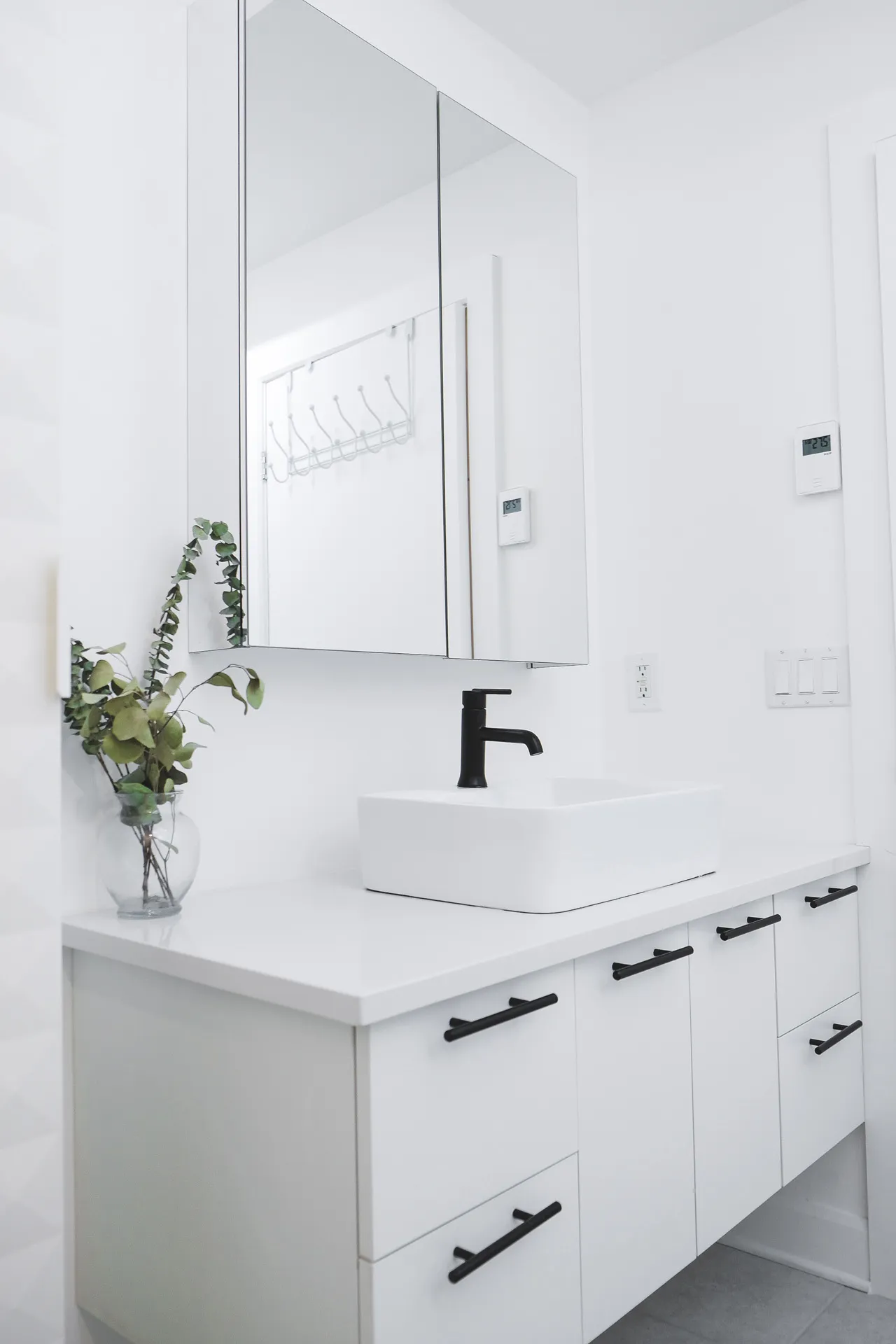 Modern white bathroom with custom vanity, white quartz countertop, framed mirror and black faucet fixtures