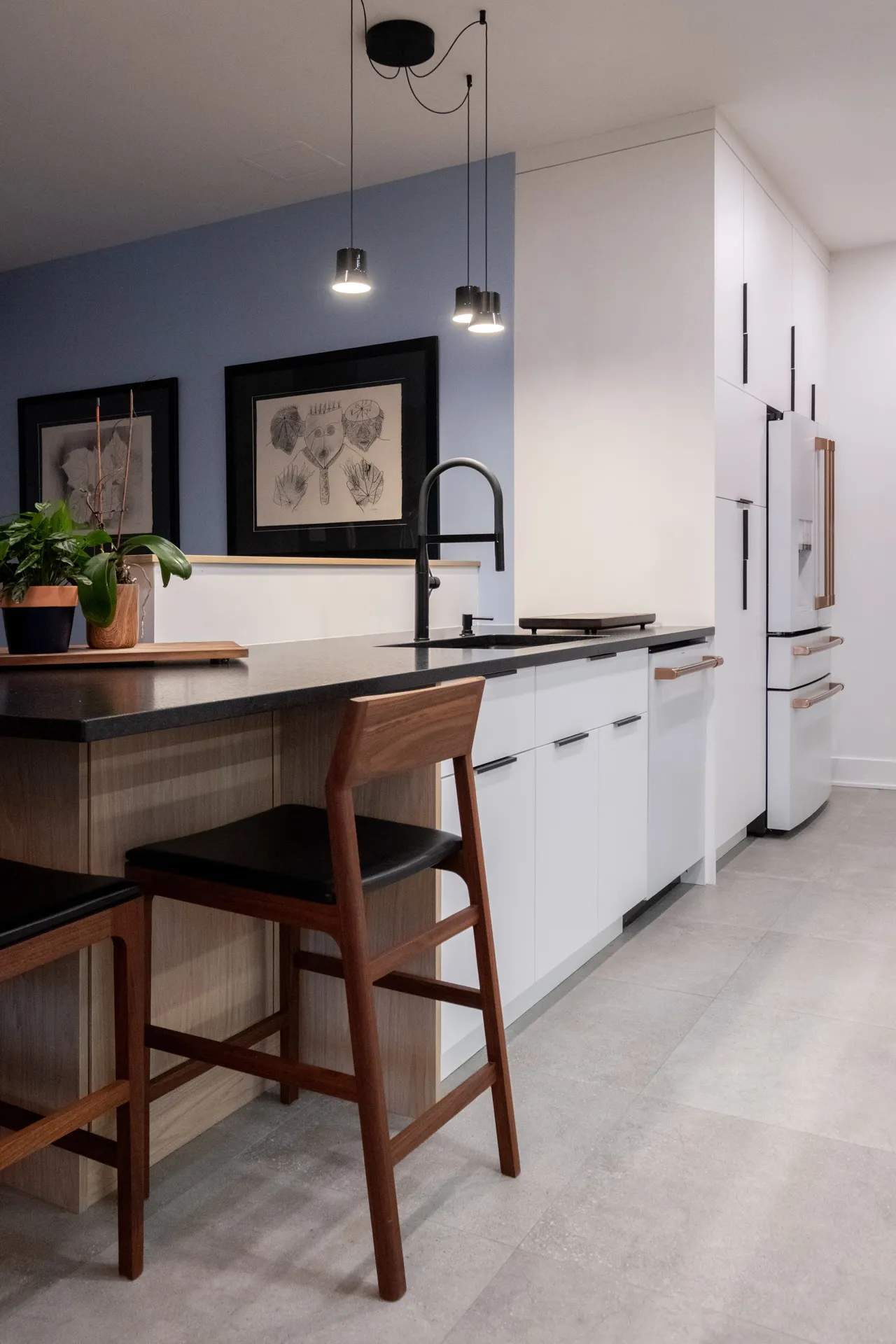 Cuisine moderne Pelletier Montréal : armoires blanches, comptoirs noirs, îlot bois, murs bleu-gris, luminaires suspendus