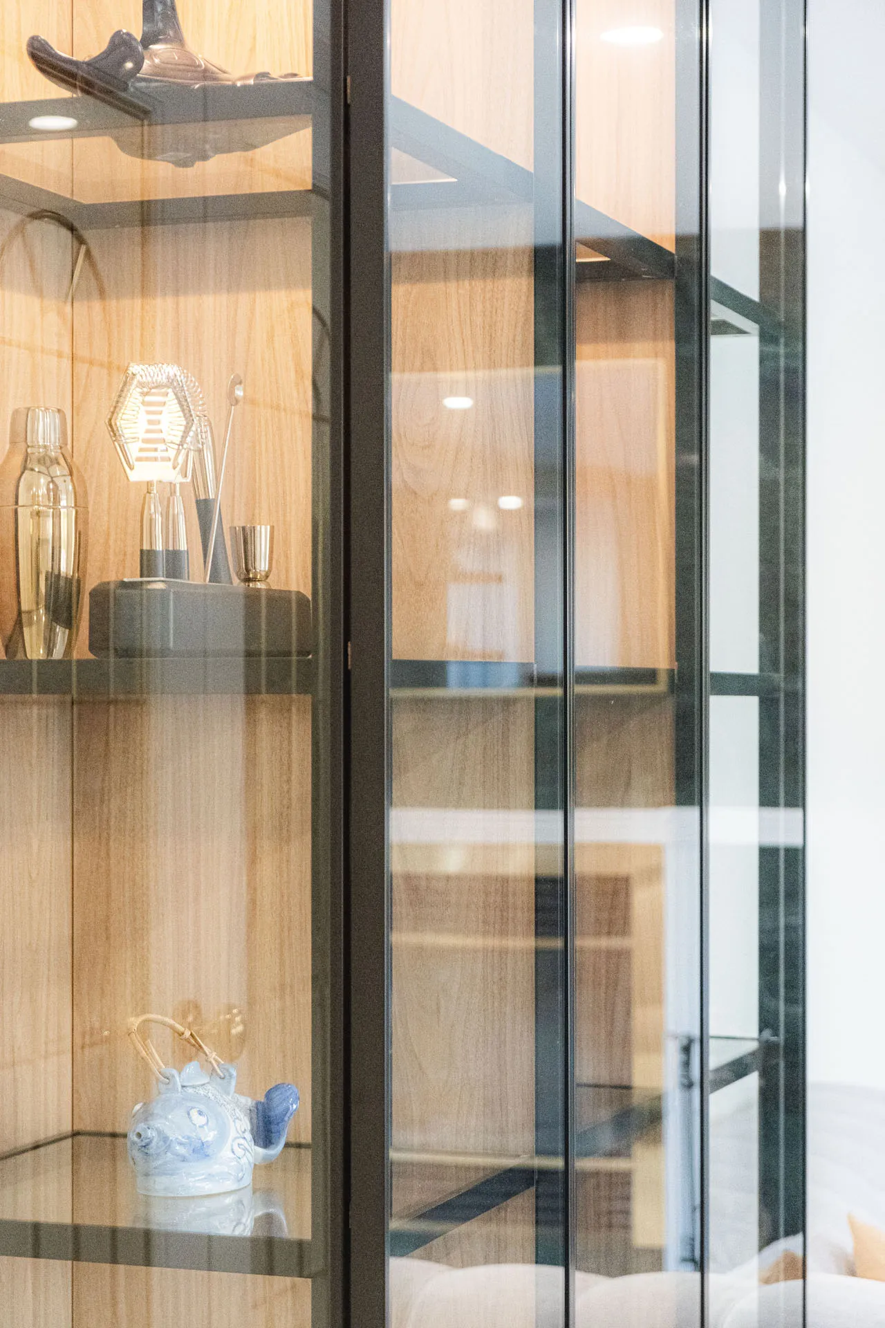 Armoires de cuisine en bois clair avec portes vitrées et rangements ouverts, comptoir foncé, luminaires intégrés