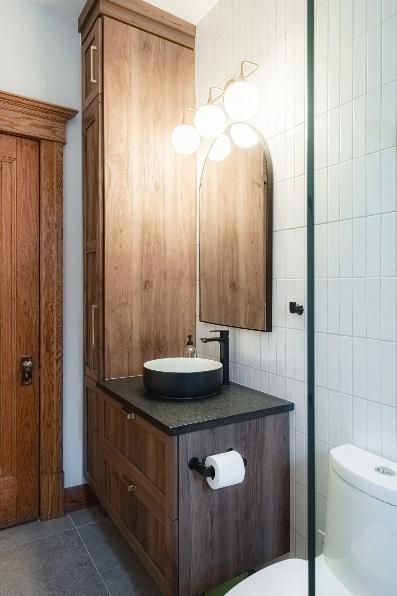 Modern bathroom with dark wood vanity, grey slate countertop, wood mirror and 4-globe pendant light fixture