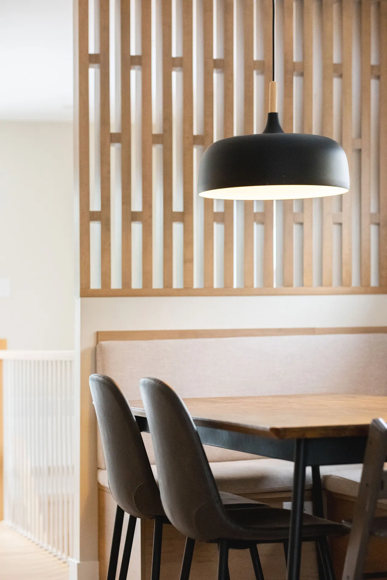 Cuisine moderne Blainville : armoires bois clair, table noire, chaises grises, luminaire suspendu noir, dosseret bois ajouré