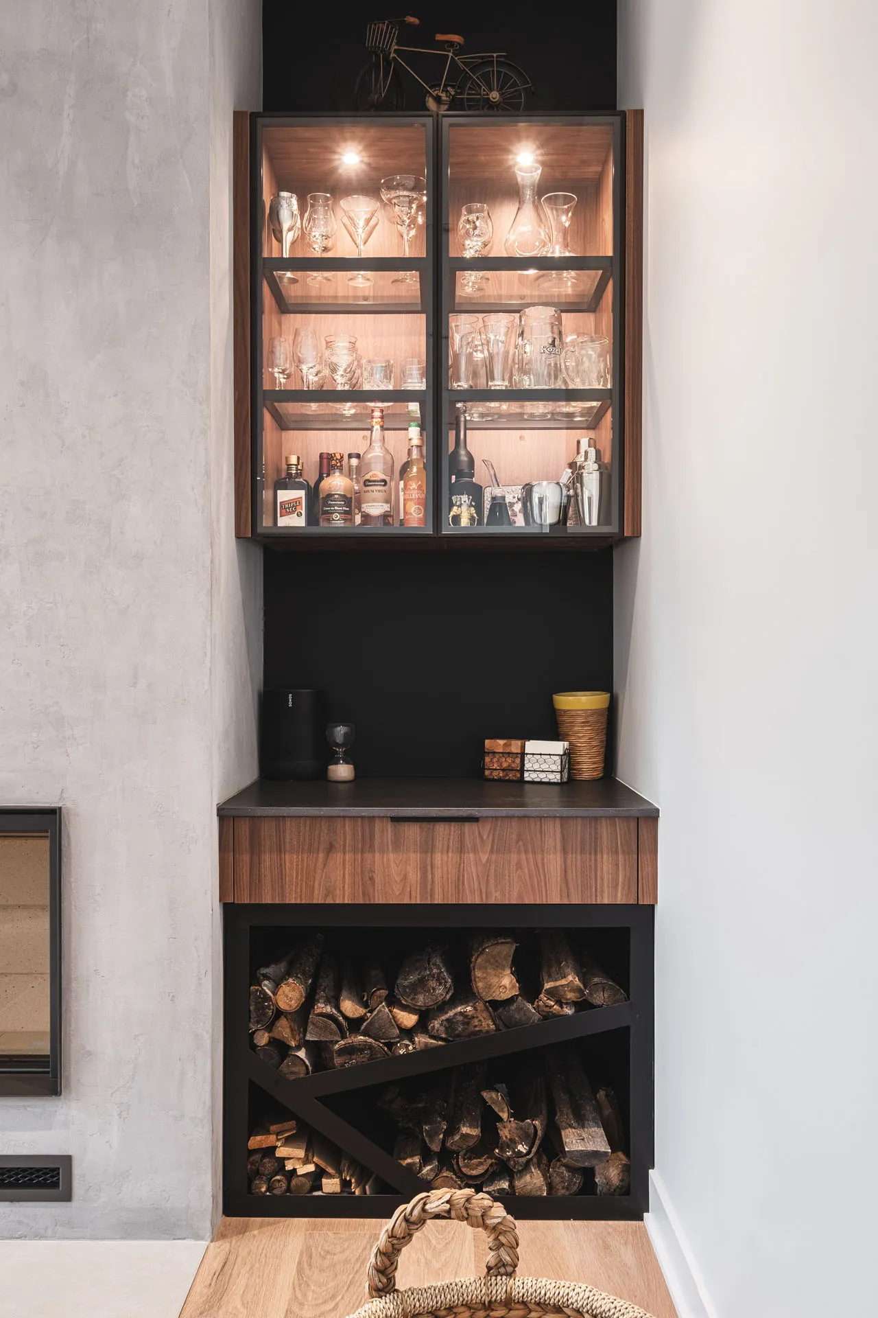 Modern black and wood bar cabinet with lit display case, slate countertop and firewood storage