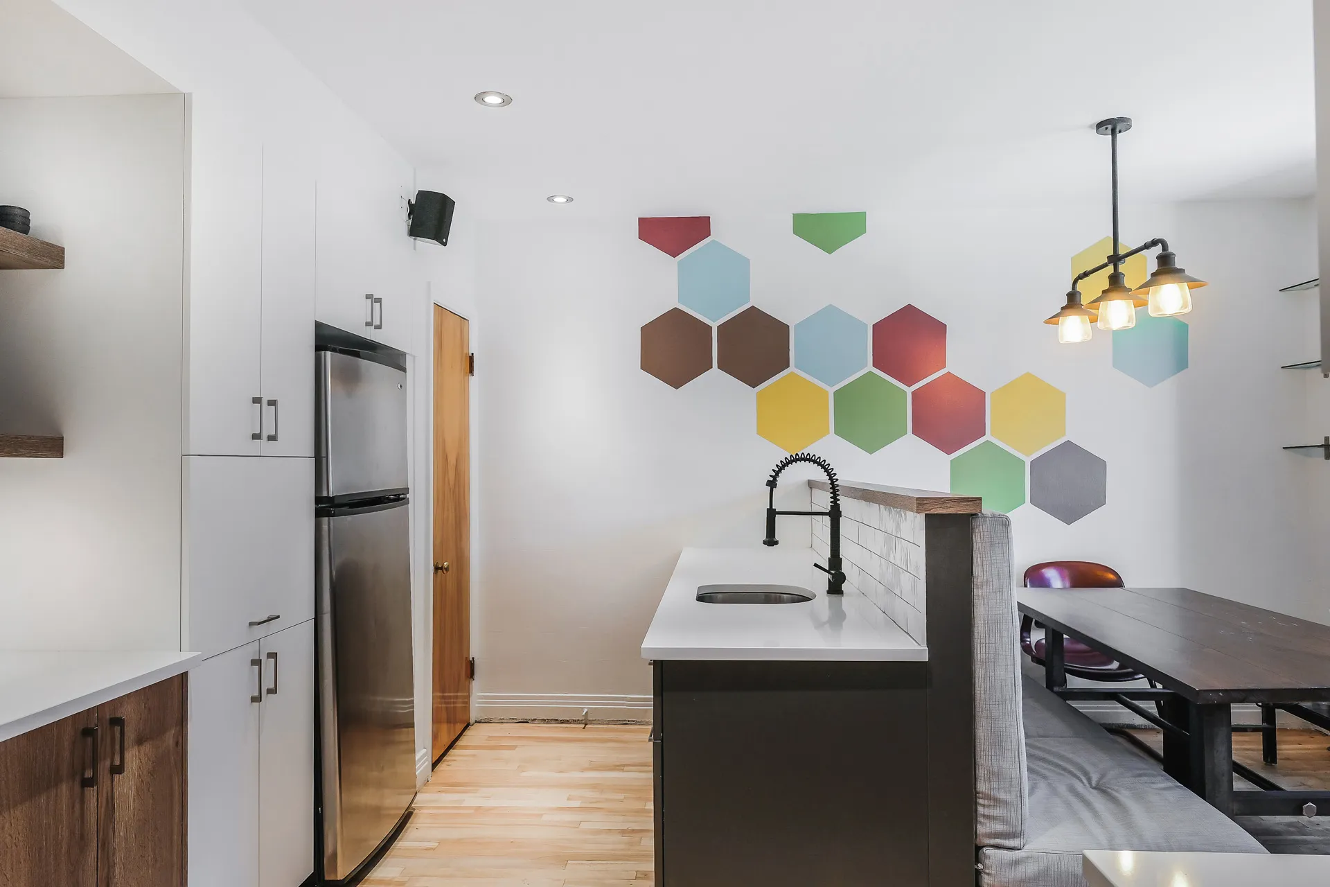 Modern kitchen with white and wood cabinets, white countertops, black island, subway tile backsplash, colorful hexagon accent wall