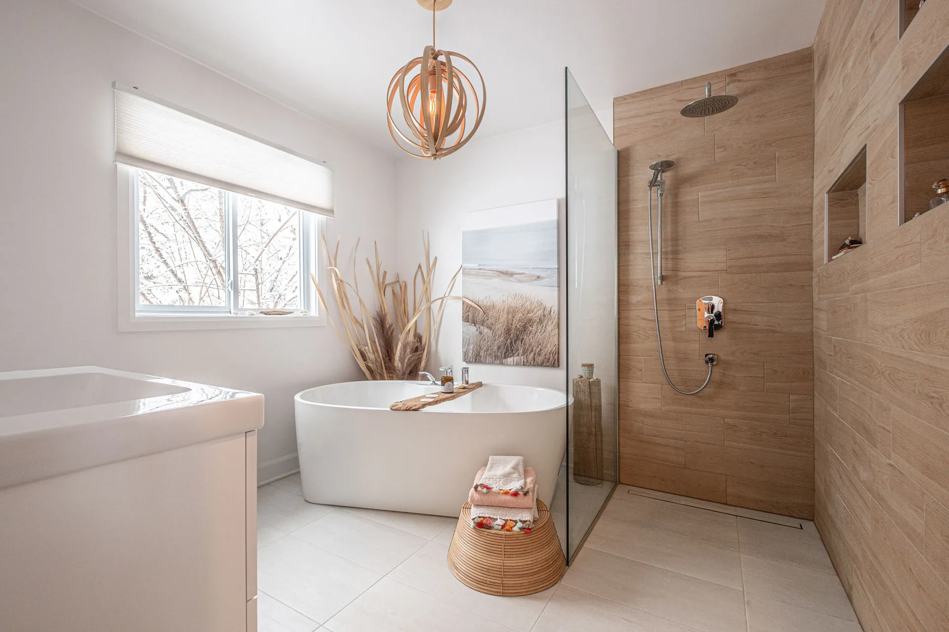 Modern bathroom with white freestanding soaking tub, wood-tiled walk-in shower, copper geometric pendant light