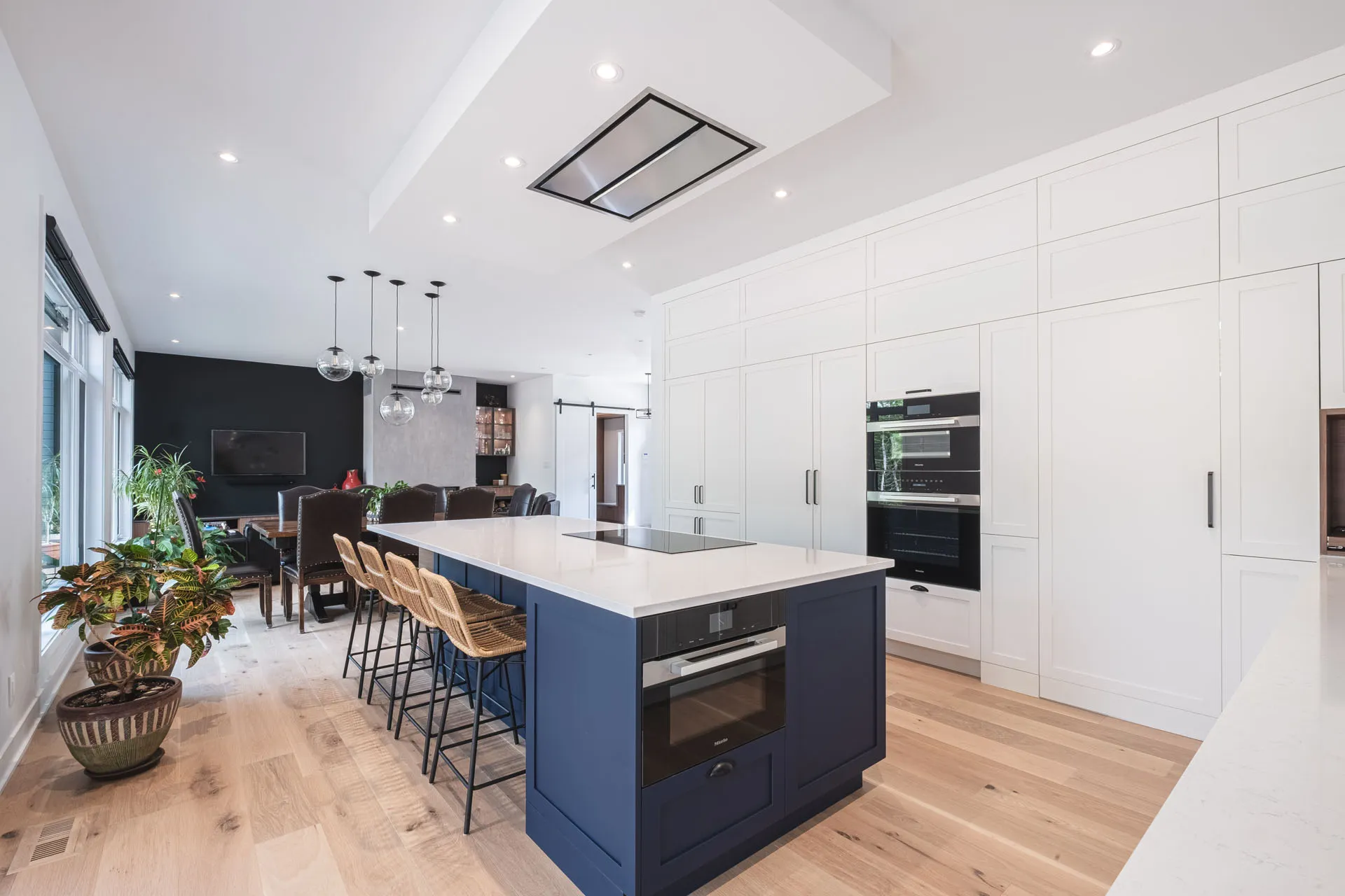 Modern Diard kitchen: white cabinetry and blue island, white countertop, black appliances, pendant lights