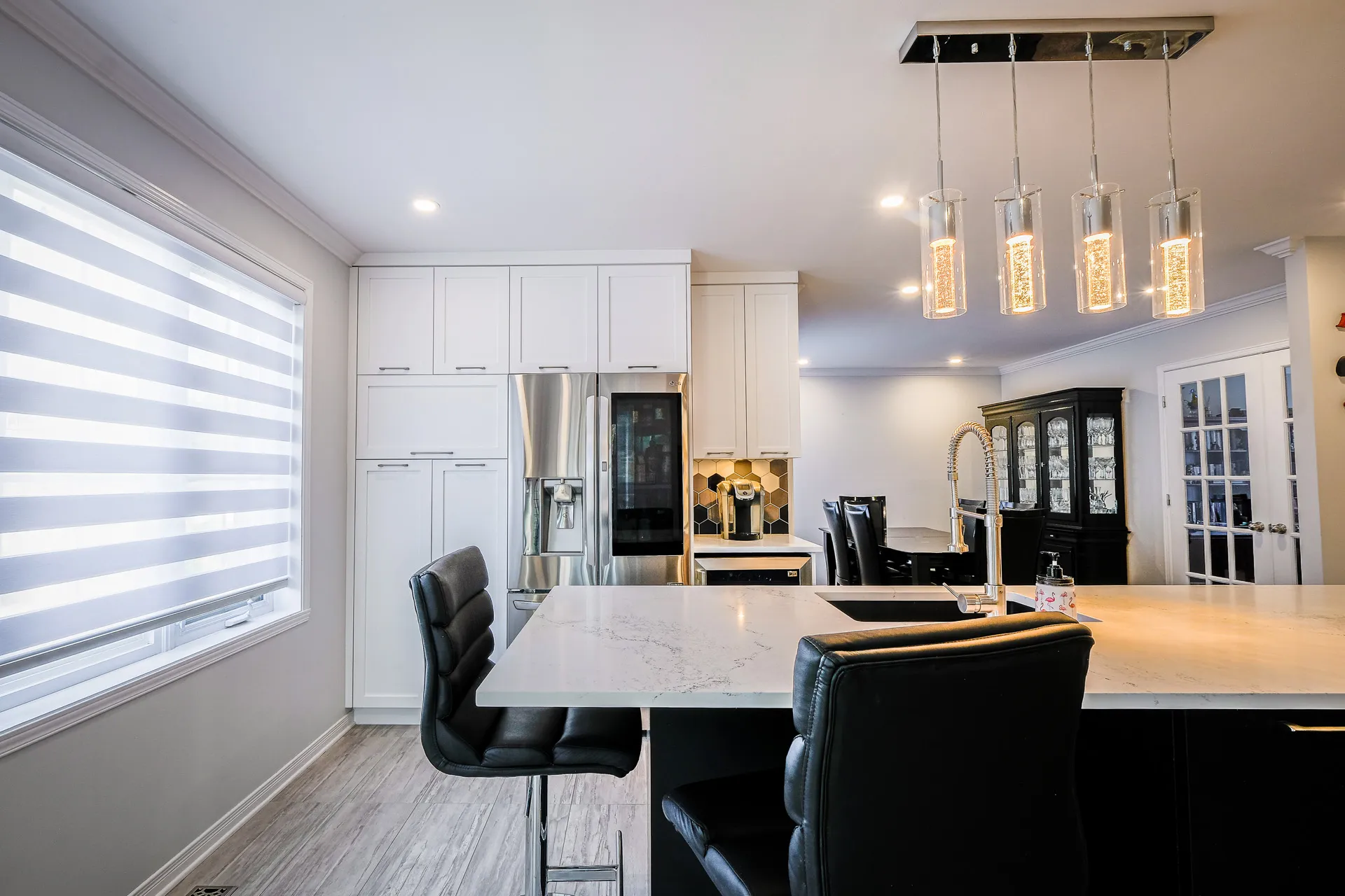 Landry kitchen Boisbriand: white cabinets, marble countertops, black island, pendant lighting, Menuitech renovation