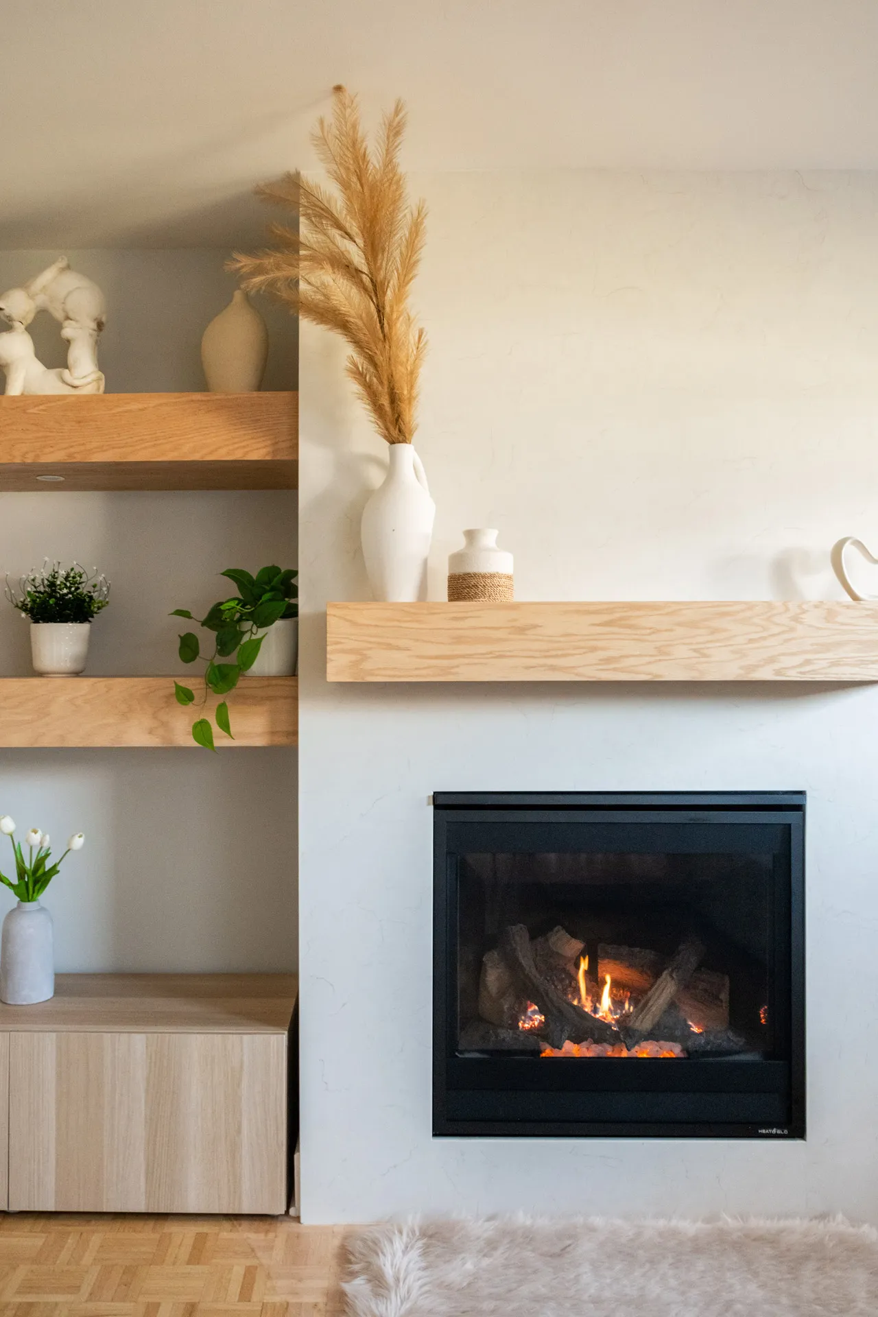 Salon moderne Menuitech avec foyer encastré, étagères bois clair, armoires blanches, décor minimaliste nordique