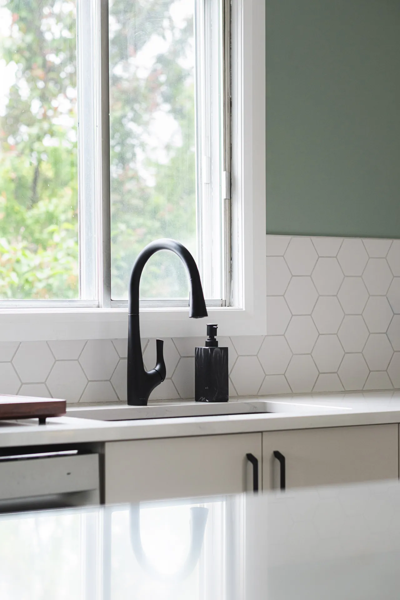 Barrett-Toth kitchen: white cabinets, white countertop, grey hexagonal backsplash, black arched faucet, window