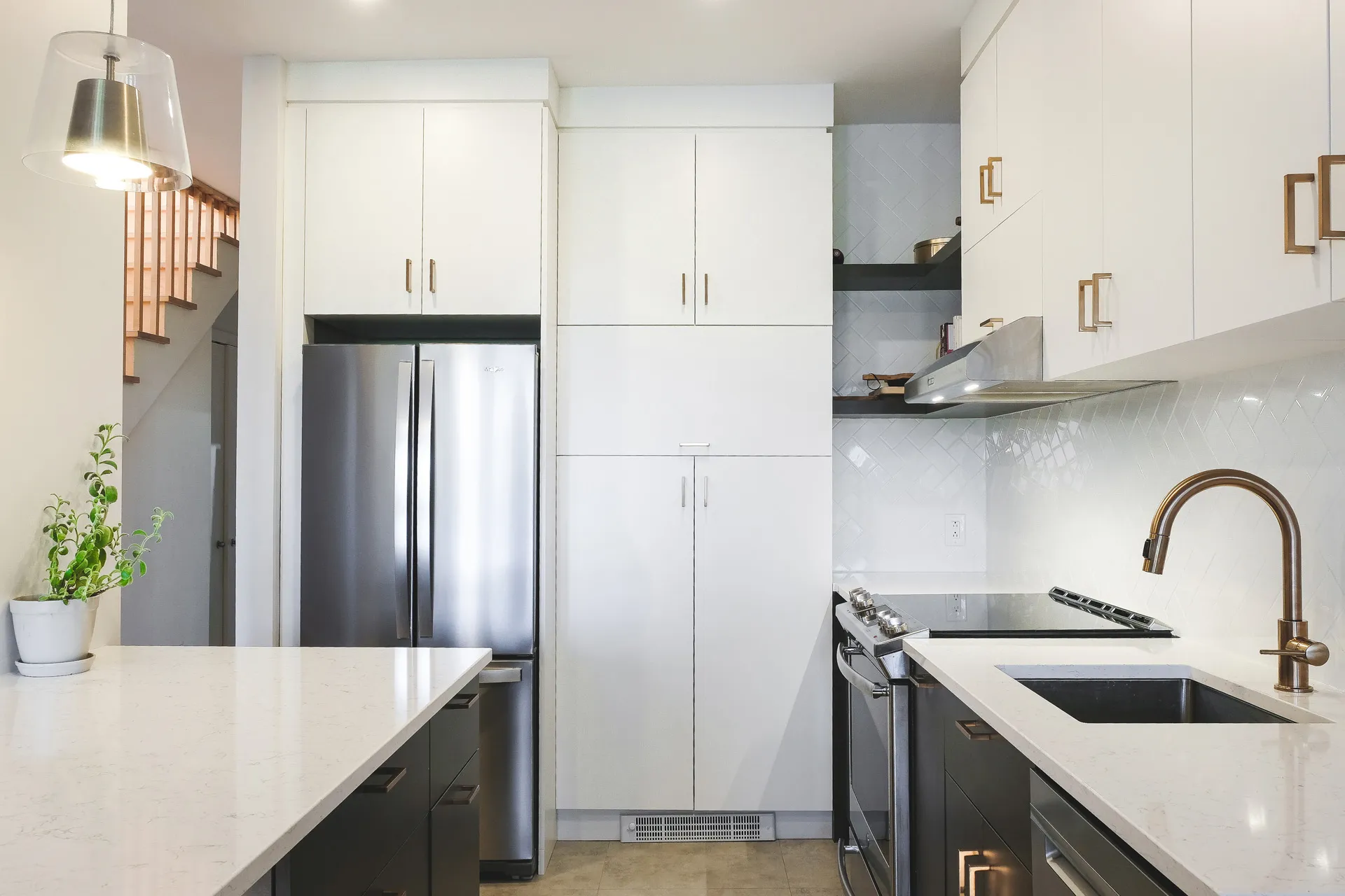 Modern Cavanagh kitchen: white and black cabinets, quartz countertop, tile backsplash, stainless steel refrigerator.