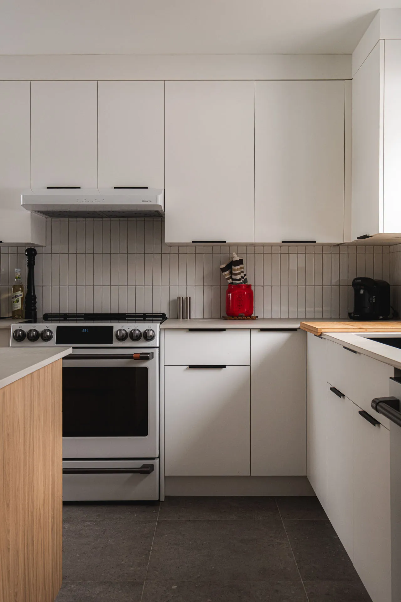 Robitaille Kitchen Épiphanie: minimalist white cabinets, white countertops, wood island, grey tile backsplash, stainless steel appliances