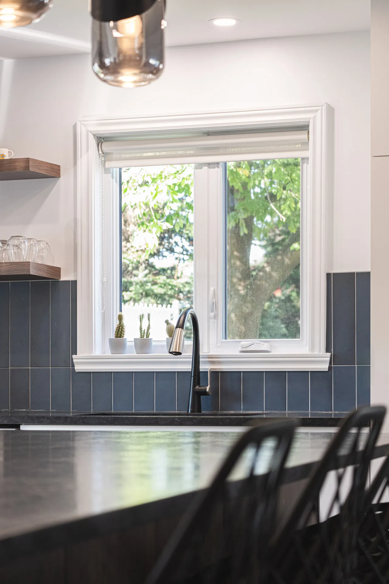 Modern Menuitech Denis kitchen Montreal: white cabinets and slate blue tile backsplash, black countertop, sink under window