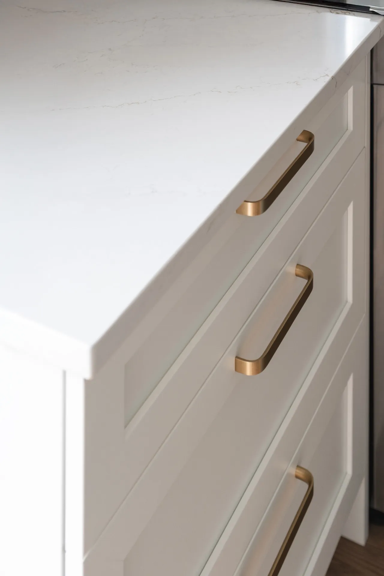 Cream white kitchen cabinets with bronze handles, white marble countertop, Pépin-Bélanger project Mascouche Menuitech