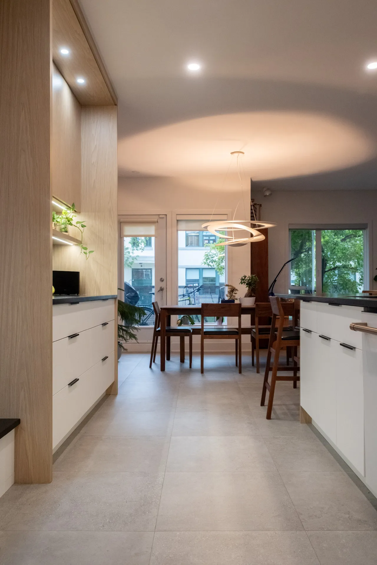Cuisine moderne Menuitech Pelletier Montréal : armoires blanc et bois naturel, comptoir gris, luminaire suspendu design, îlot central
