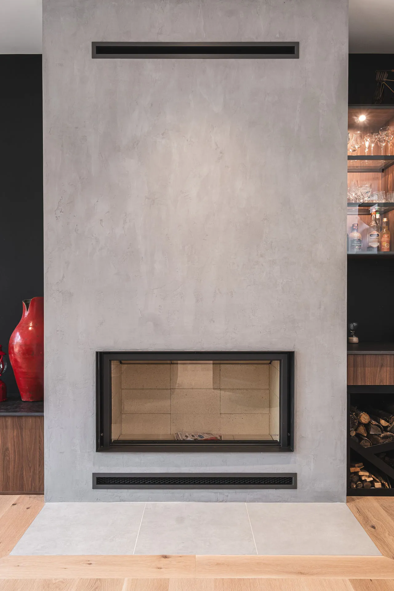 Modern living room with built-in fireplace, light gray concrete walls, black frame, wood and black storage, minimalist décor