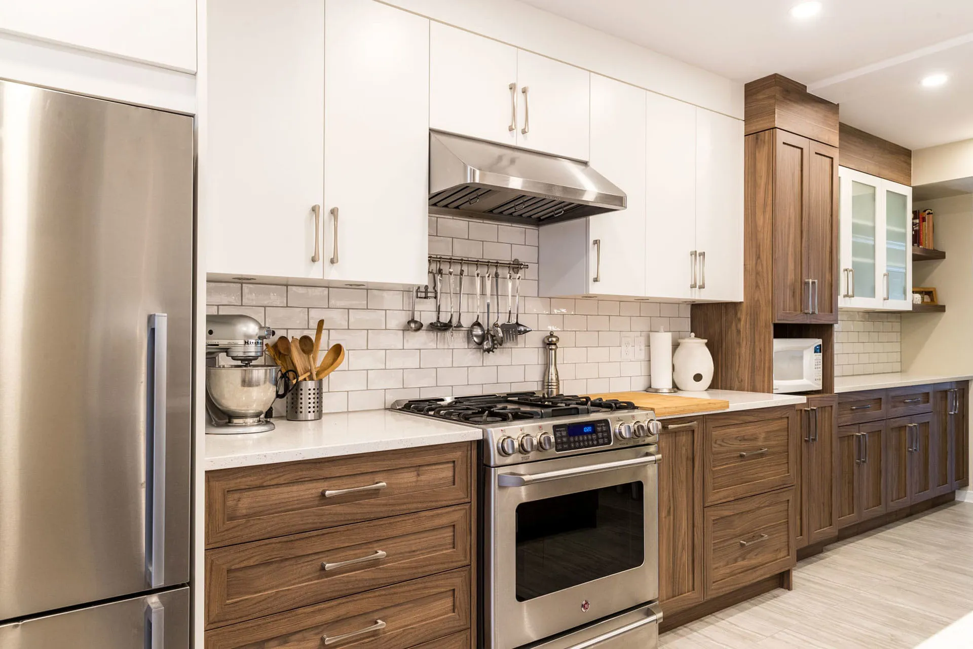 Mathieu Kitchen Montreal: white and walnut cabinets, white countertop, wooden island, subway tile backsplash, stainless steel range